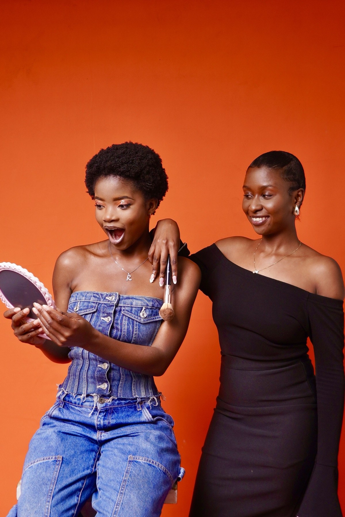 A makeup artist and model sharing a joyful mirror moment